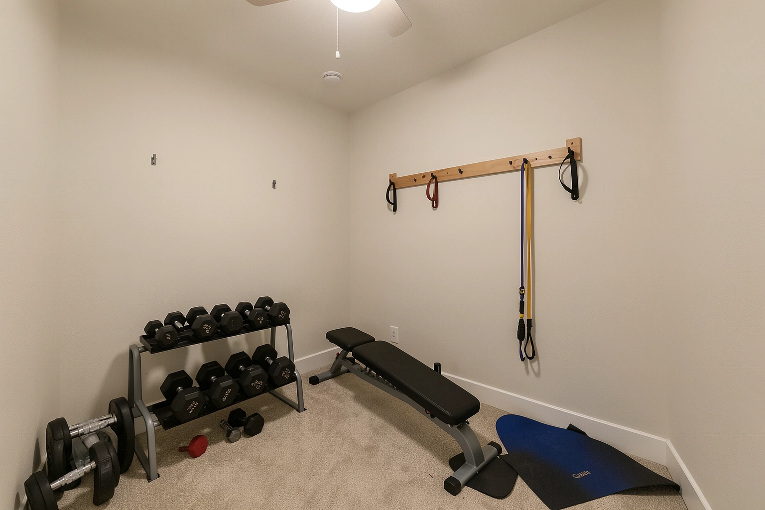 Compact home gym layout with dumbbells, mat, and bench