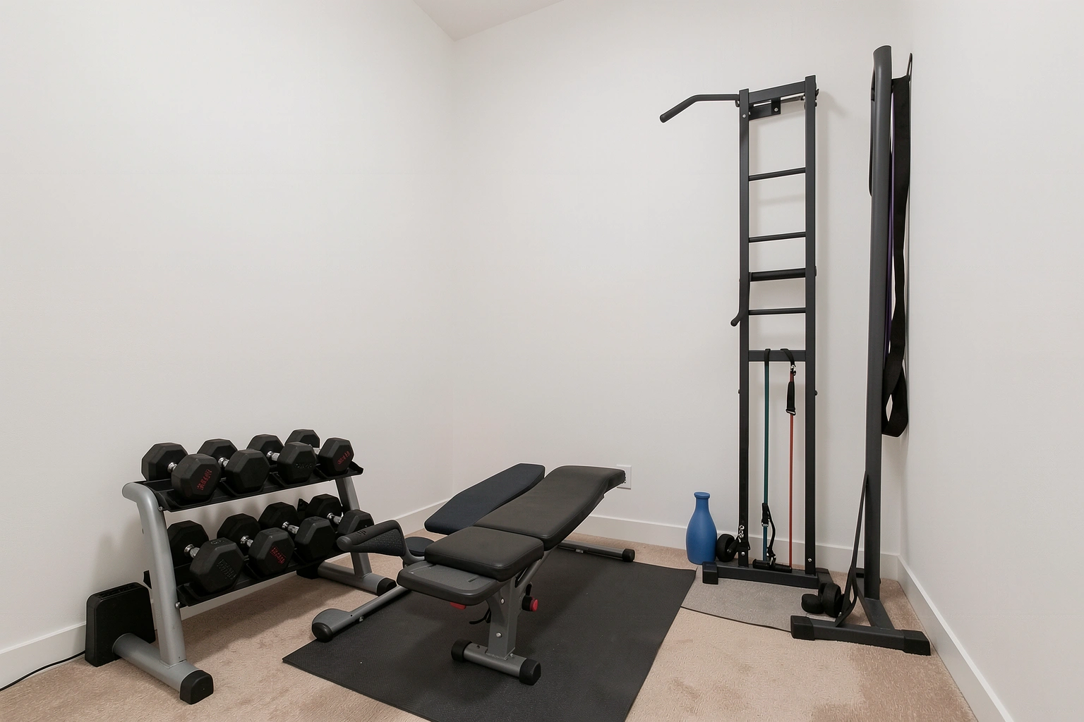 Compact home gym with dumbbells, bench, bands, and storage
